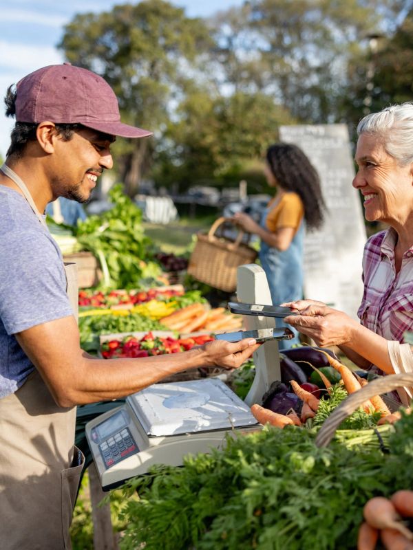 Woman paying with phone at farmers market.