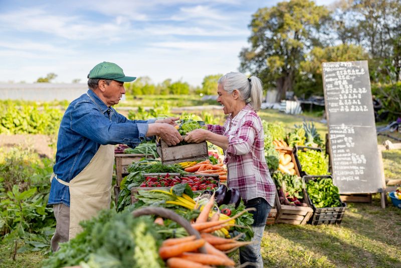 Latin American farmer selling organic vegetables to a happy customer at a Farmer's Market - small business concepts