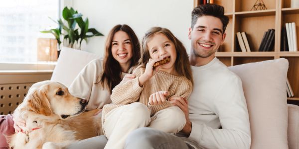 Happy family with their dog smiling on a couch.