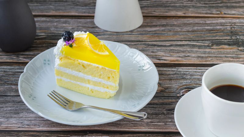 Bakery Lemon Cream Cake in a plate with hot black coffee on a wooden background