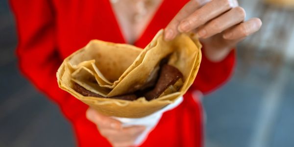 Person holding a folded crepe with chocolate inside.
