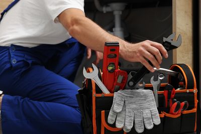 Worker reaching for a wrench from a toolbox.