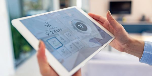 Person using a tablet to control smart home temperature settings.