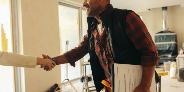 Two people shaking hands, one holding documents.
