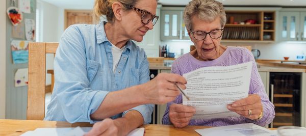 Two women reviewing documents together at a kitchen table.