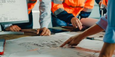 People reviewing blueprints at a work table.
