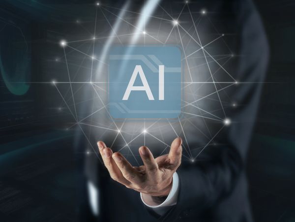 Businessman holding a glowing AI symbol connected by network lines.