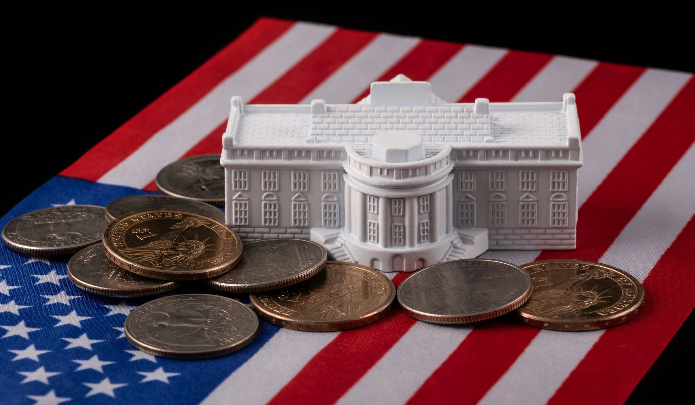 Model of the White House with coins on an American flag.
