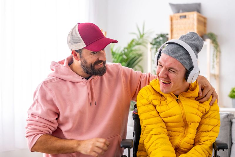 Smiling disabled man and caregiver during art therapy session with music at home