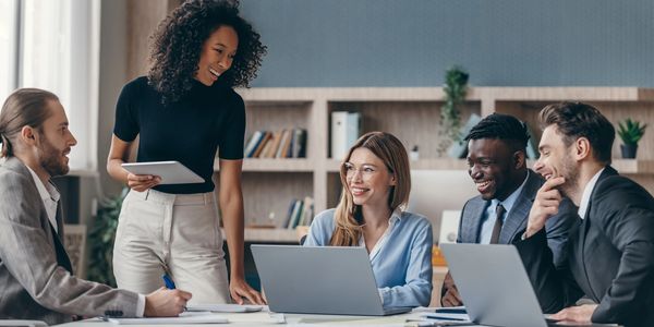A diverse group of colleagues collaborating and smiling in a modern office meeting.