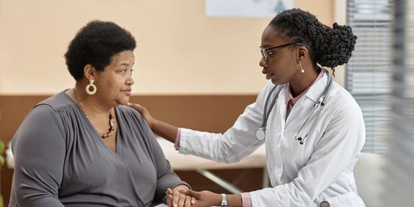 Doctor consoles patient during a consultation in a medical office.
