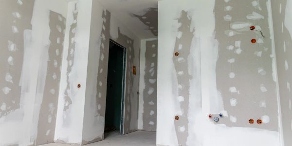 Unfinished drywall installation in a room under construction.