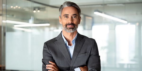 Confident mature businessman with arms crossed in modern office.