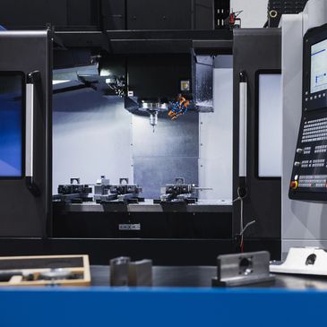 Close-up of a CNC machining center with control panel and metal parts.