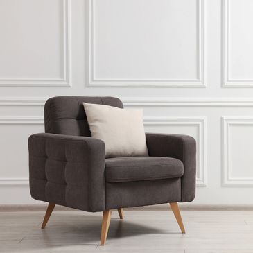 Modern dark gray armchair with a beige cushion in a bright room.