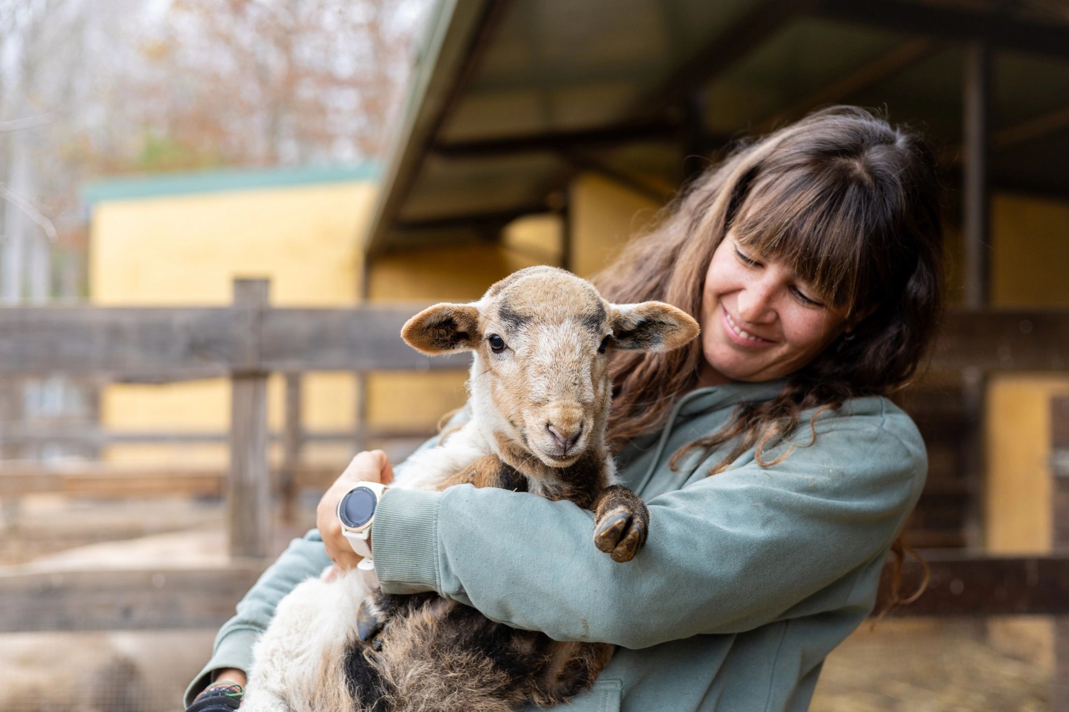 Woman smiling while holding a sheep.