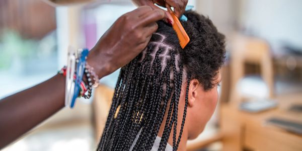 Person braiding another's hair with a comb.