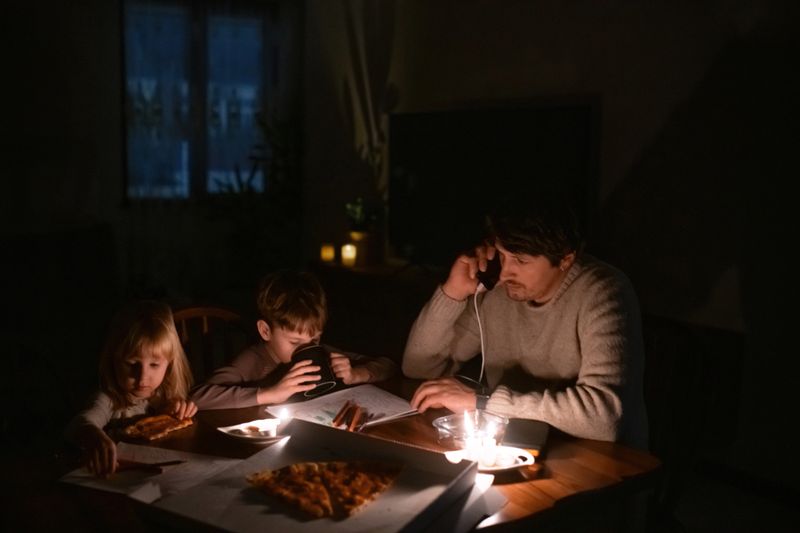 Family sitting at home with candles during blackout.