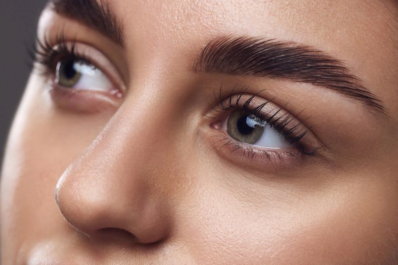 Close-up of a woman's eyes with well-defined eyebrows, long lashes, and smooth skin, highlighting meticulous grooming. Concept of mascara brand, lash volume and eye enhancement. Ad