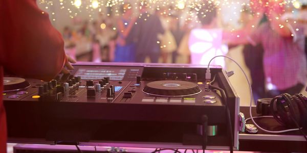DJ mixing music at a lively party with dancing crowd and sparkling lights.