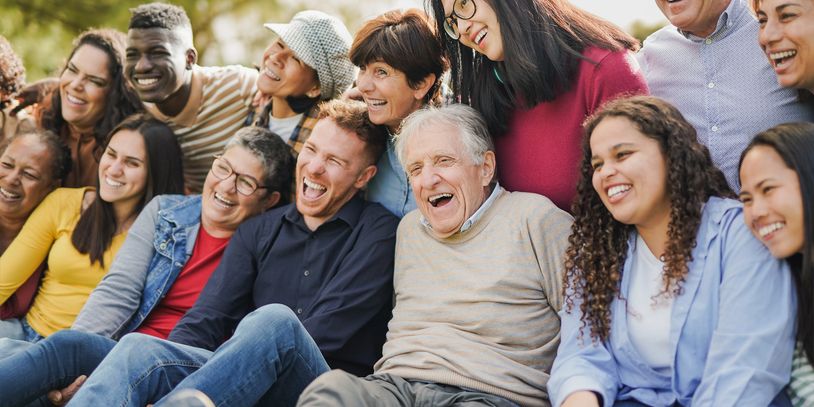 Diverse group of people laughing together outdoors, enjoying each other's company.