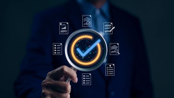 Person holding magnifying glass with checkmark and icons around.