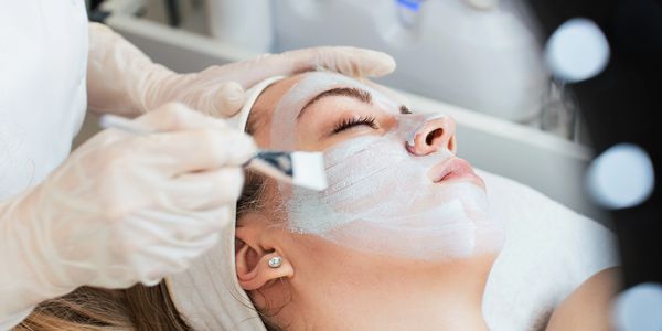 A woman receiving a facial mask treatment at a spa.
