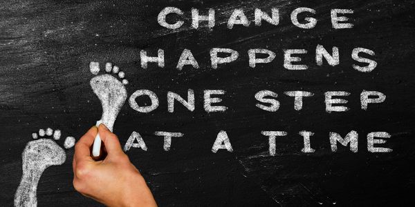 A chalk board with the statement "Change happens one step at a time."