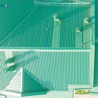 Aerial view of a turquoise rooftop with vents and shadows.