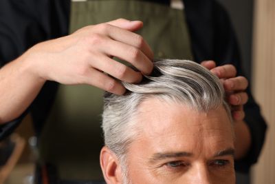Stylist styling a man's gray hair.