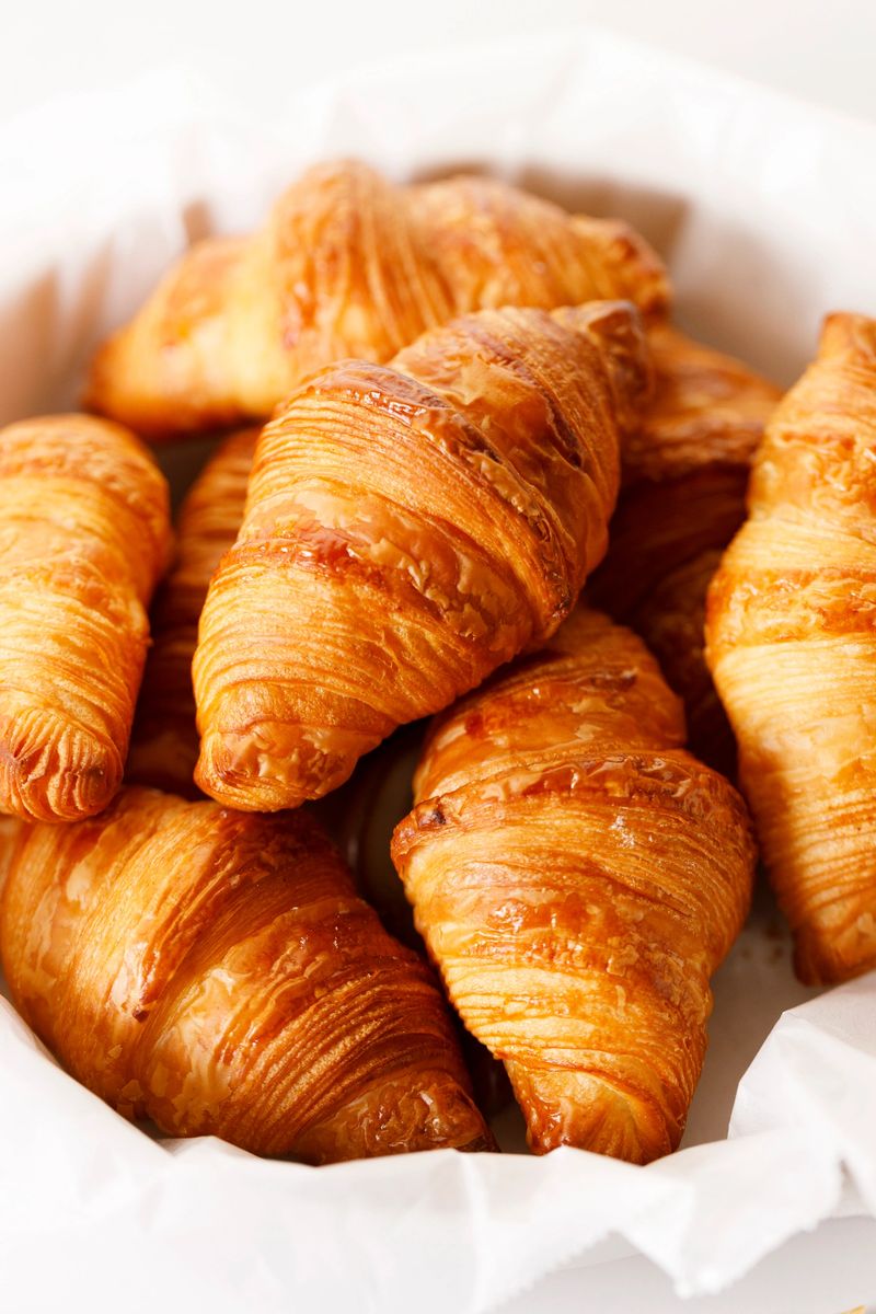 Fresh baked croissants on white table background. Closeup.