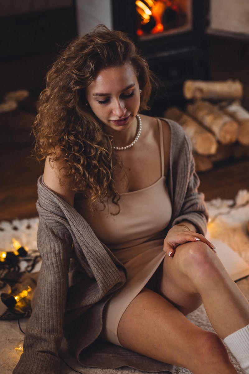 Young beautiful attractive woman at home, wearing casual soft clothes. Winter, countryside house, fireplace. Cozy home holiday atmosphere, country interior, warm light