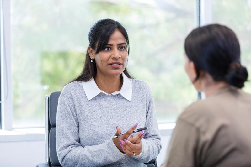 The mid adult female mentor sits in her office and meets with her colleague to review her career goals before beginning the program.