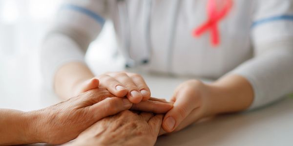 A comforting handhold between a healthcare worker and an elderly patient.