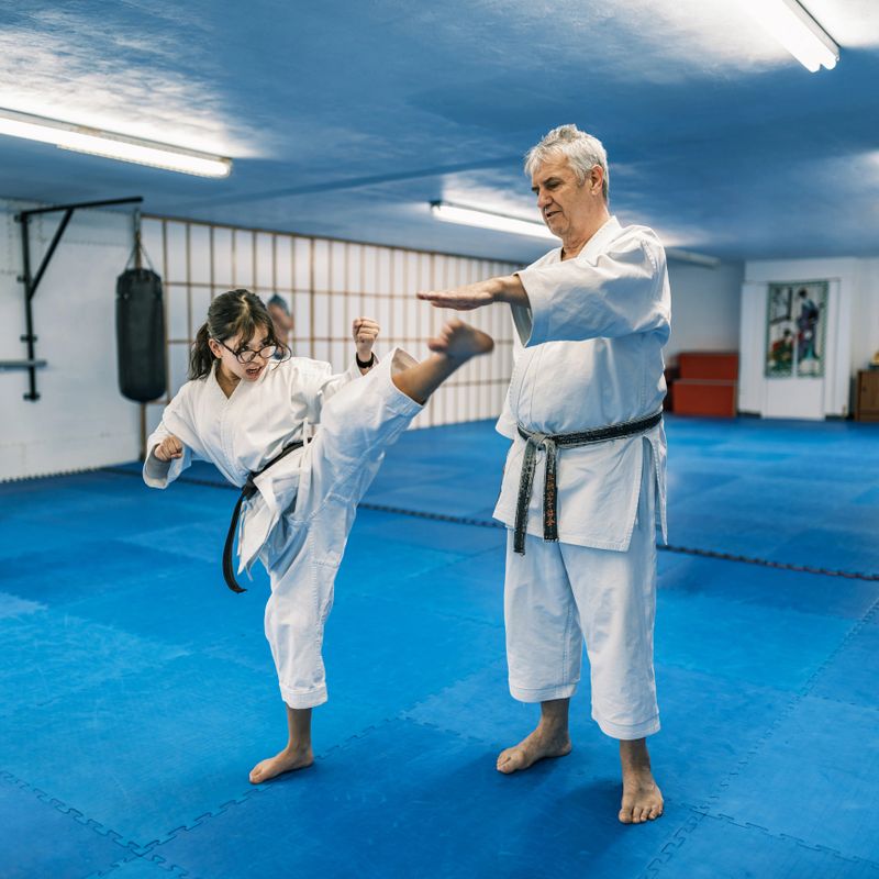 Sensei (karate master) teaching Young Karate fighters in karate school. They are all dressed in karategi-karate uniform. Interior of karate school in Mississauga, Ontario in Canada.