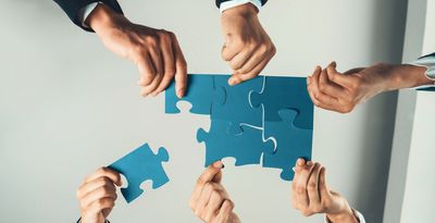 A group of people holding up puzzle pieces.