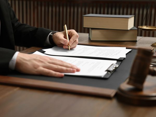Professional signing document with pen on desk.
