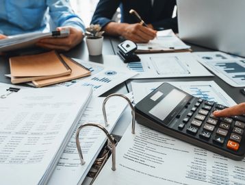 Business team analyzing financial documents with calculator and notes.