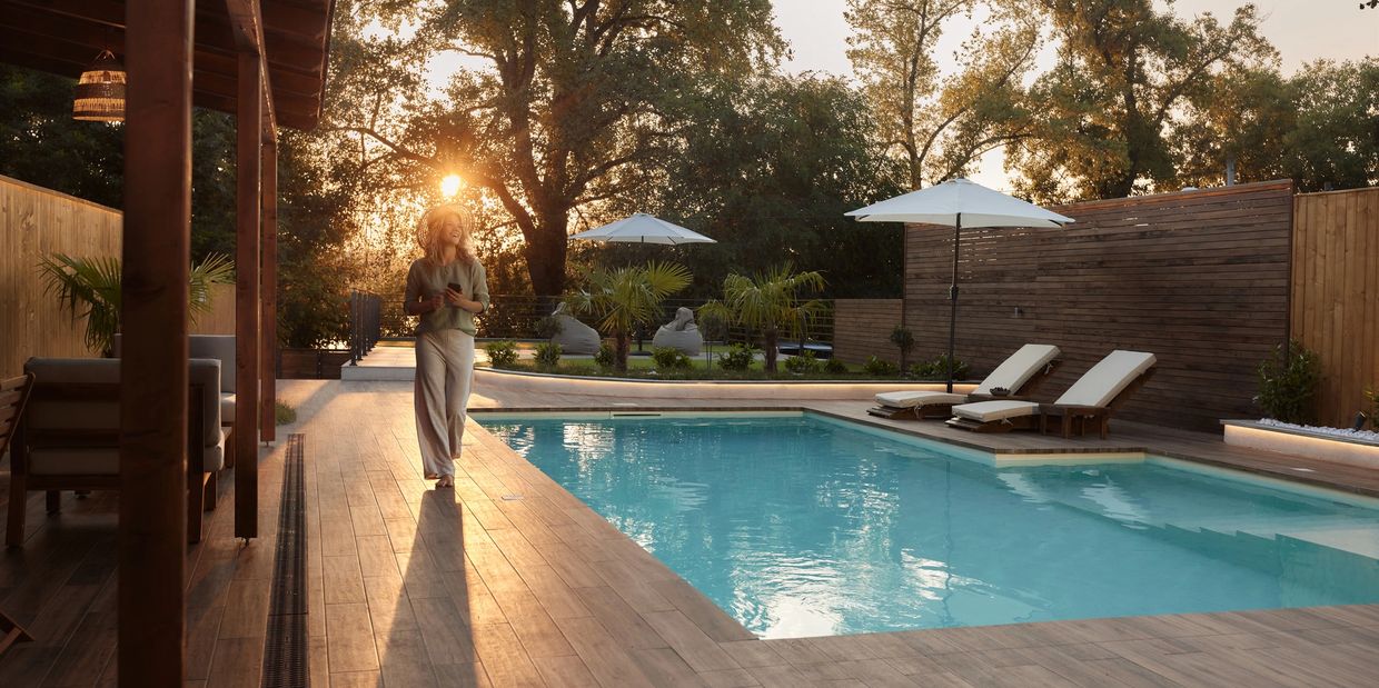 Woman walking by a pool at sunset.