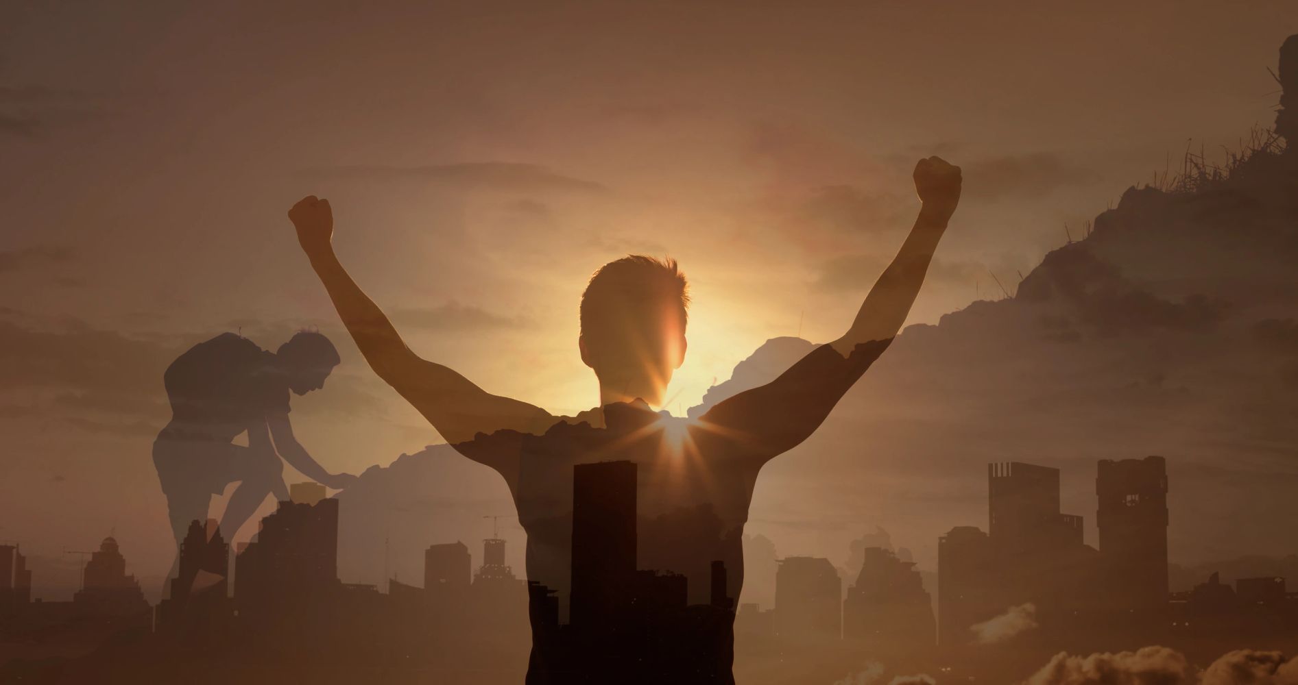 Silhouette of a victorious person with arms raised during sunset.