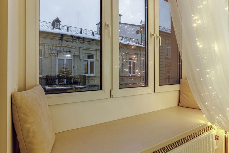 Window sill with soft pillows, illuminated by a New Year's garland.