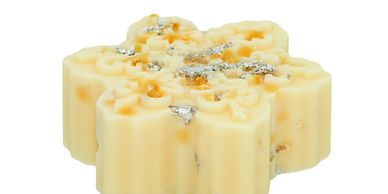 A cream-colored flower-shaped soap with silver flakes on top.