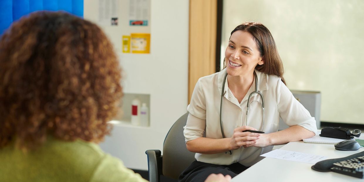 Doctor smiling and talking with a patient during a consultation.