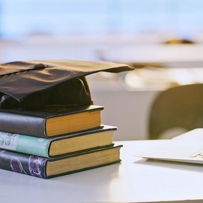 Graduation cap on stacked books symbolizing academic achievement.