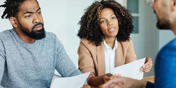 a couple talking to a person holding a paper in their hands