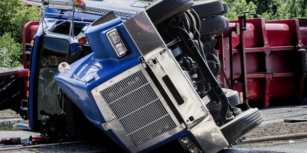 A blue truck overturned on its side on the road.