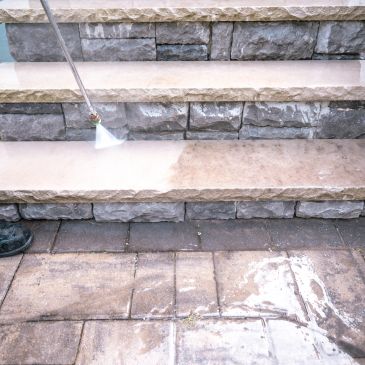 Pressure washing stone steps and pavement for cleaning.