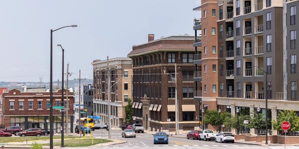 Urban street with buildings and cars under clear sky.
