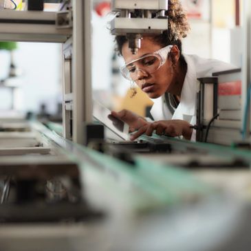 Scientist inspecting machinery in a lab with safety goggles.