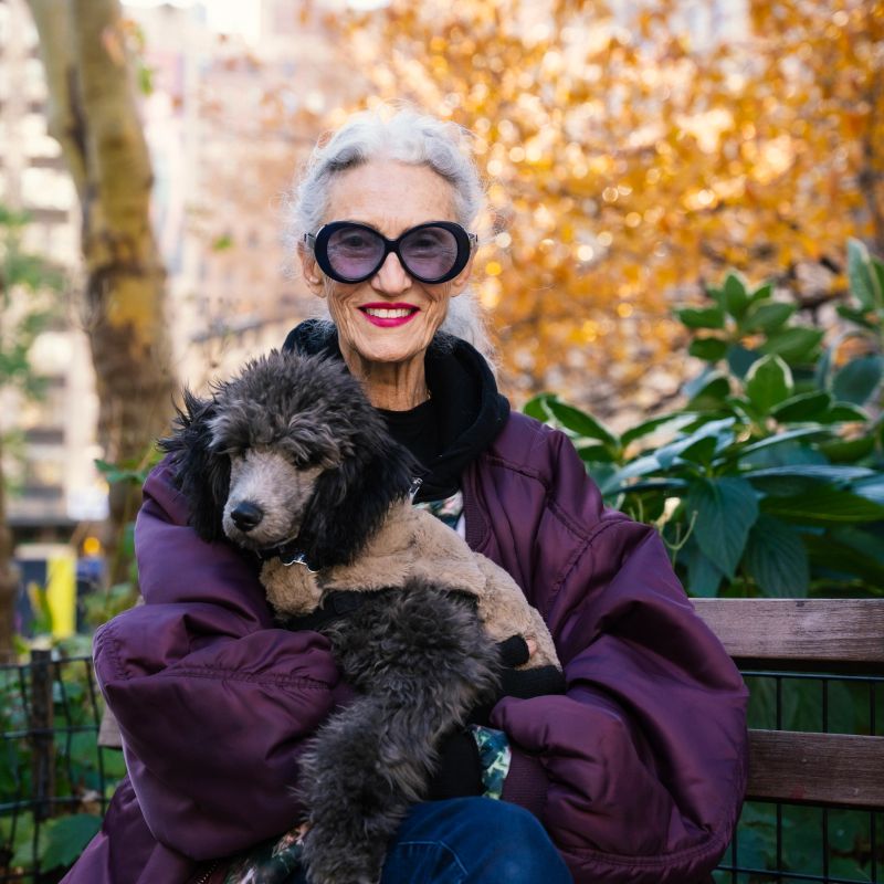 Happy senior woman posing with her dog in Madison Square Park, New York City